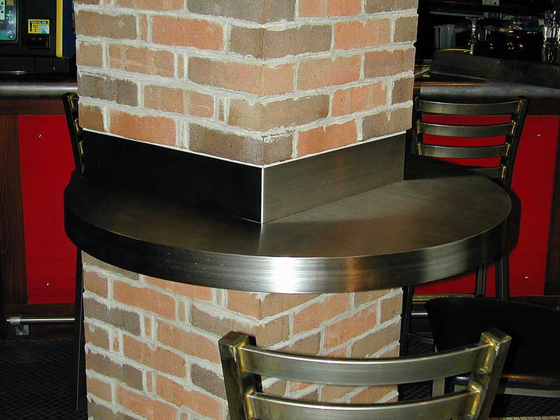 Custom stainless steel bar table counter attached to brick column.