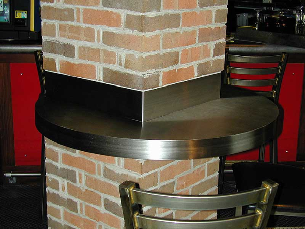 Custom stainless steel bar table counter attached to brick column.