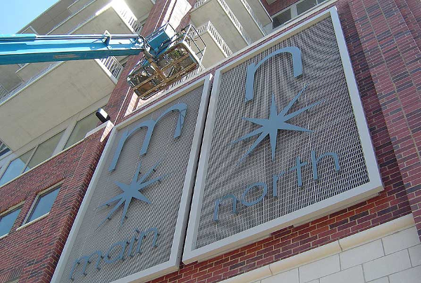 Custom fabricated water jet cut exterior sign is hoisted by crane into place at Main North Loft's