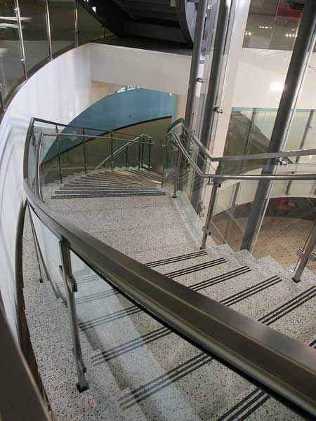 Tempered curved glass railings with custom stainless steel post, glass clamps and handrail.