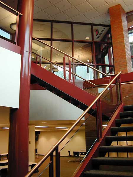 Switchback metal stair with glass and brass handrail.