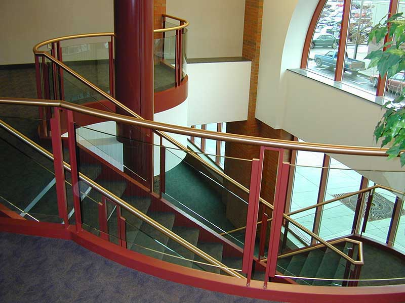 View of curved brass and glass railings at balcony.