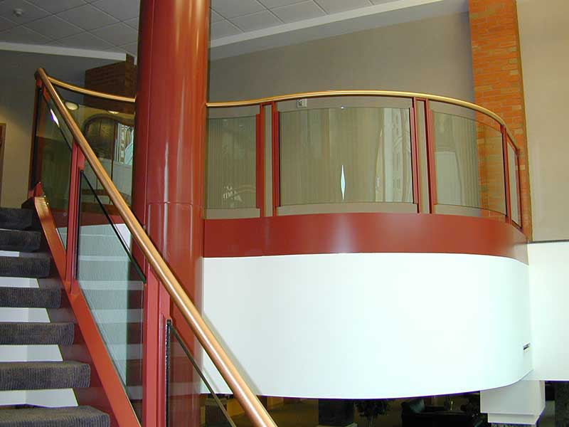 Glass railings at balcony with brass pipe top handrail.