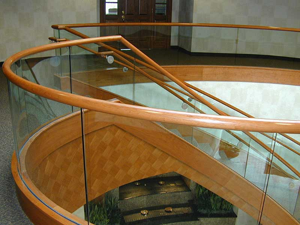 Custom wood railing on top of curved glass railings